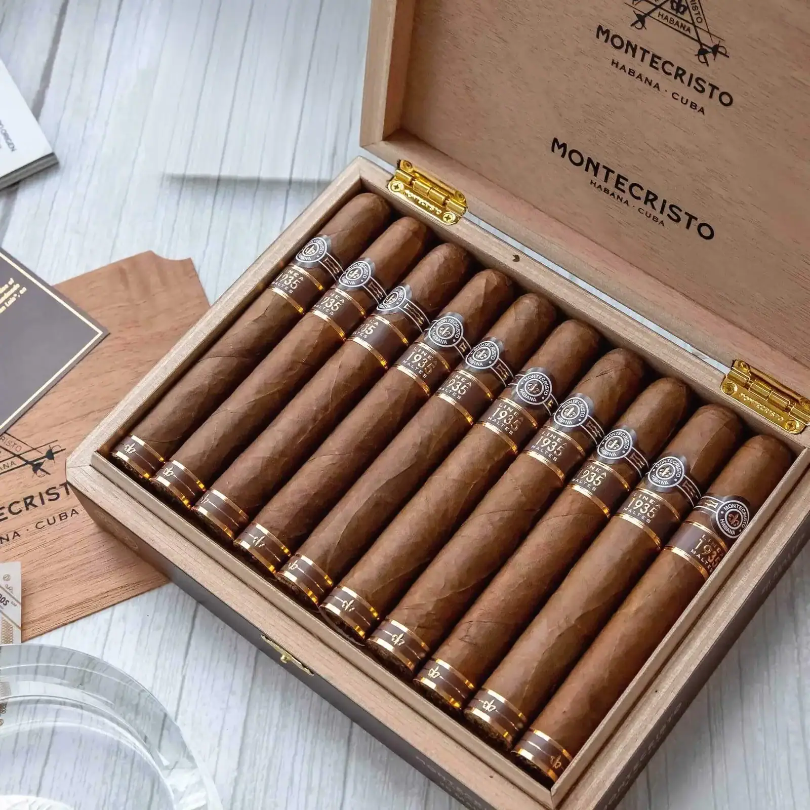 Cutie deschisă Montecristo Linea 1935 Maltés cu trabucurile aranjate în rânduri pe masă, evidențiind rulara manuală și tutunul cubanez premium.
